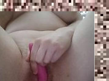 A woman with big titis masturbates with a pink vibrator and cums